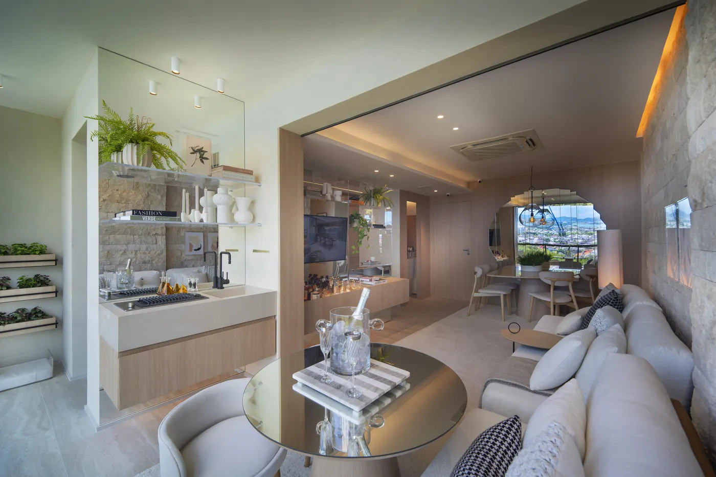 Varanda e sala do decorado de 2 suítes, com sofá claro e mesa redonda