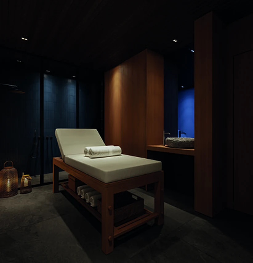 Sala de massagem com maca de madeira e luz baixa
